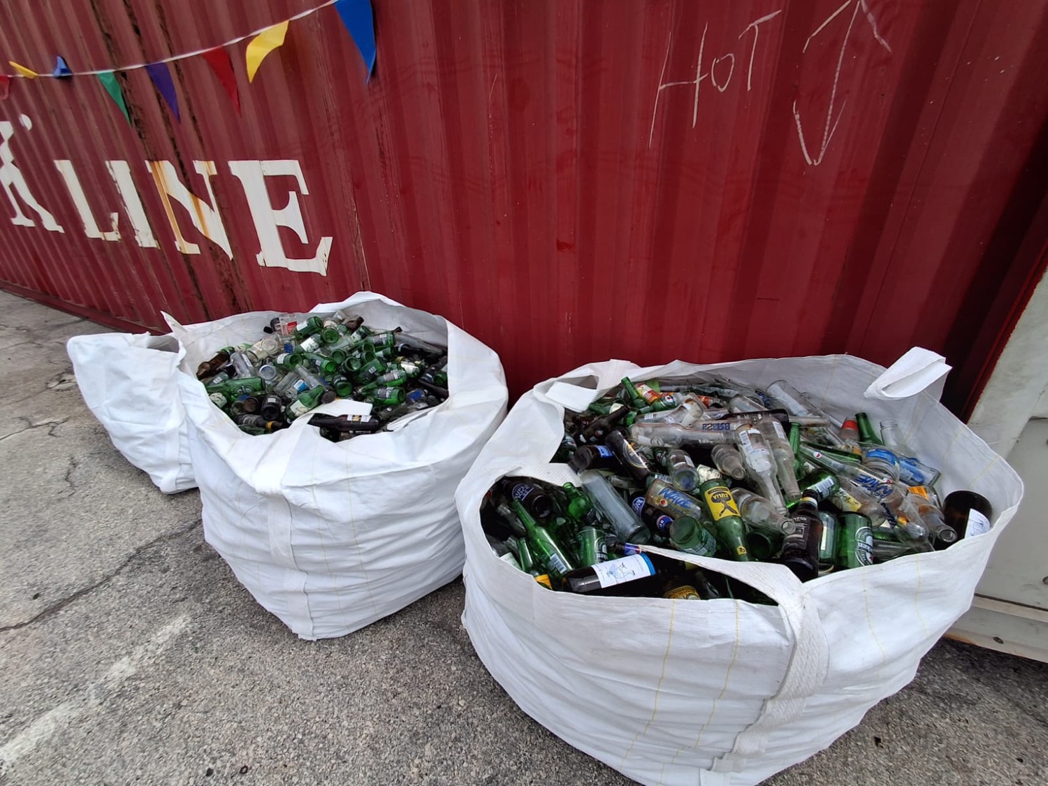 Big bags of glass next to the collection container